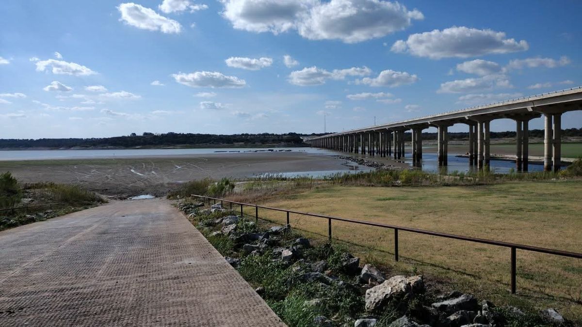 Lake Belton at very low water, with a long walkway leading to a receded shoreline and the highway bridge in the distance